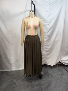 Détail d'une jupe plissée élégante en vert olive foncé avec un tissu tissé drapé