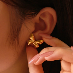 Minimalist 18K gold plated bow earrings in titanium steel shown on a female model