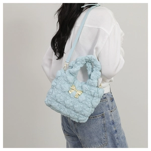 Light blue bubble pleated nylon crossbody bag with golden bow worn on shoulder