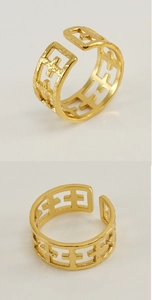 Detail view of golden open ring with hammered texture and hollow cross pattern design