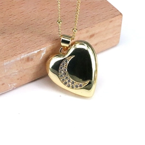 Golden heart pendant necklace with micro-paved moon zircon on a wooden display stand