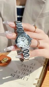 Montre en acier argenté avec cadran en nacre et chiffres romains sur le poignet d'une femme