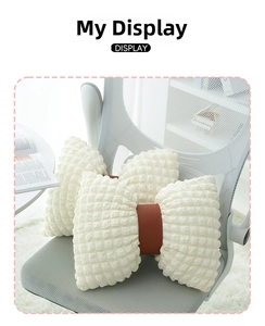 Macro detail of cream bow-shaped waffle fabric pillow with brown leather strap accent