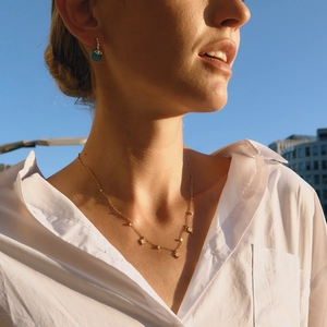 Collier étoile doré et boucles d'oreilles gemme bleue sous la lumière naturelle