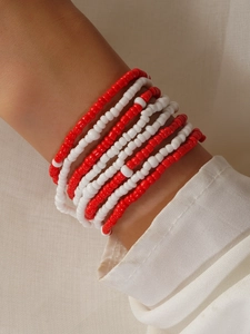 Detail of multi-layered red and white beaded bracelet on woman's wrist with soft lighting