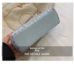 Detail view of the flat light blue leather base and gold metal ring handle of the bag
