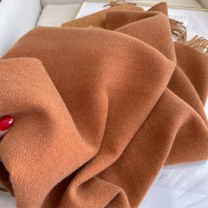 Detail showing the soft caramel cashmere blend fabric texture and fringe of the winter scarf