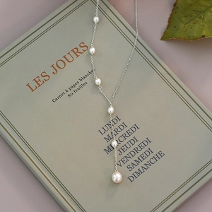Detailed view of elegant freshwater pearl Y-necklace on a French book background