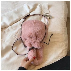 Gros plan sur le sac seau en peluche rose avec bandoulière en cuir noir réglable