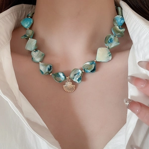 Detailed close-up of a bohemian necklace with teal beads and a gold shell pendant