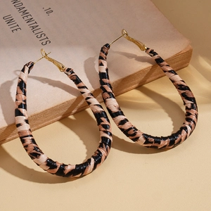 Close-up of leopard print leather teardrop earrings on a vintage book with warm shadows