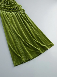 Detail of green velvet dress showing knot design and pleated texture on the waistline
