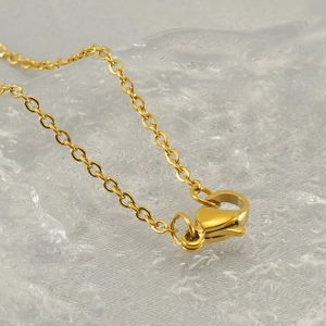Gold stainless steel square alphabet necklace featuring a lobster clasp on an ice background