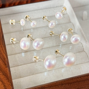 Macro shot of assorted pearl stud earrings with pink luster in a white velvet jewelry box