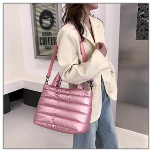 Detailed side view of pink quilted puffer tote bag worn by model in a modern room
