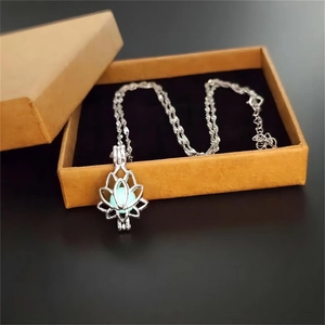 Detailed view of silver lotus locket necklace with light blue bead in a brown gift box