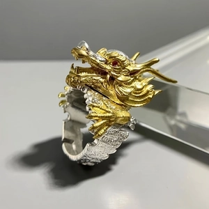 Macro detail of vintage dragon ring featuring gold head with red eyes and silver scales