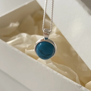 Elegant 925 sterling silver necklace with a round turquoise pendant on a gift box