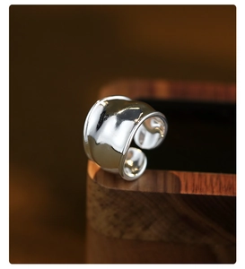 Macro shot of silver wide twisted open ring showing smooth metallic texture and glossy finish