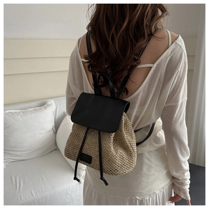 Detail of woven straw backpack featuring black faux leather flap and adjustable straps
