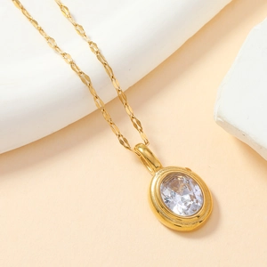 Détail d'un collier en acier titane doré avec un pendentif serti d'une gemme transparente