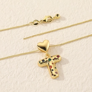 Macro shot of gold box chain and heart clasp with colorful zircon letter T pendant