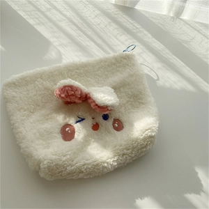Close-up of white plush bunny makeup bag with pink ears and fine embroidery details