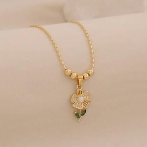 Detail of 18K gold sunflower necklace with white diamonds, pearl center and green leaves