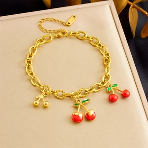 Detail of gold-plated stainless steel bracelet with red enamel cherry charms on padding