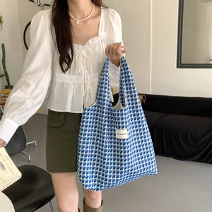 Close-up of sky blue checkered knit tote bag with woven texture and branded label