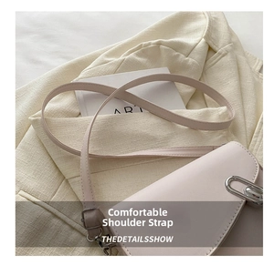 Detail of light beige leather saddle bag featuring a unique silver paperclip twist lock