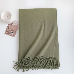 Close-up of olive green cashmere-like scarf showing soft texture and tassel details