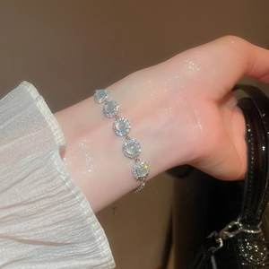 Détail d'un bracelet en argent avec opales vert clair et halo de zircon sur le poignet