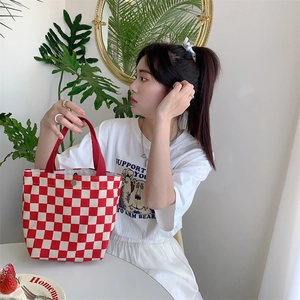 Close-up of a red and white checkered corduroy tote bag with red strap handles
