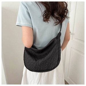 Detail of a black crossbody bag with pleated texture shown on model for daily style