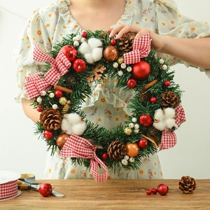 Couronne de Noël artisanale avec pommes de pin, coton et nœud à carreaux rouges décor