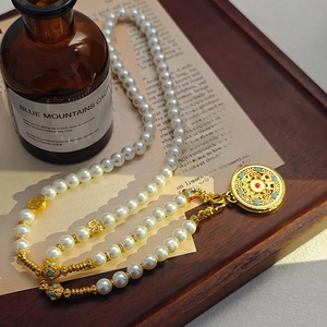Elegant gold filigree disc necklace with pearls and colorful gemstone accents on wood