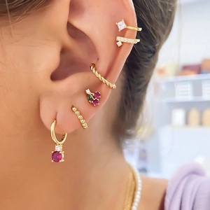 Close-up of gold cherry fruit earrings and zirconia studs set worn on model ear
