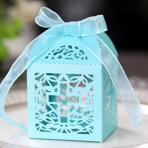 Detail of light blue laser-cut favor box with cross design and organza ribbon bow