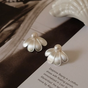 Detailed view of silver flower earrings with brushed texture and center pearl inlay