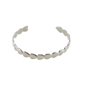 Macro view of minimalist silver heart-shaped linked open bangle with polished finish