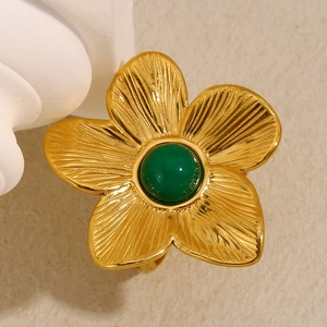 Macro detail of gold flower ring featuring turquoise stone and radial texture petals