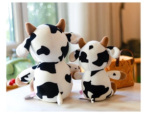 Vista trasera de adorables peluches de vaca con manchas blancas y negras en dos tamaños distintos