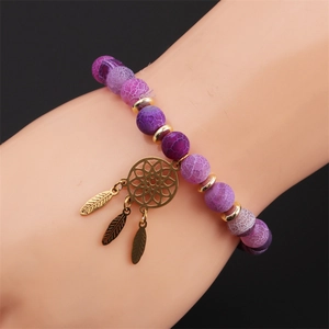 Detail of purple stone bead bracelet with a gold dreamcatcher pendant and feather charms