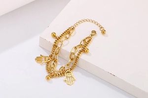 Detailed shot of double-layered gold Hamsa hand bracelet with beads on white base