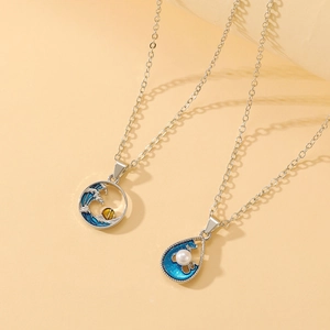 Close-up of blue wave and pearl teardrop pendants on silver necklaces with enamel detail