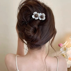 Detail of elegant black hair clip with white shell flowers worn on hair