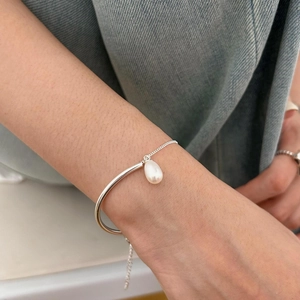 Close-up of S925 sterling silver minimalist bracelet with a teardrop pearl on a model