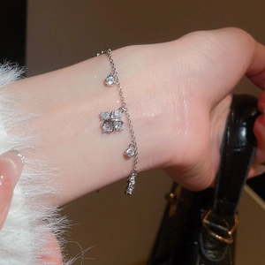 Detail of elegant silver zircon bracelet with cross flower pendant on a model's wrist