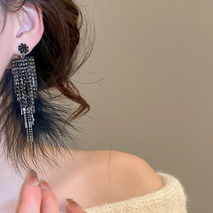 Détail de boucles d'oreilles de luxe à pompons en plumes noires avec cristaux